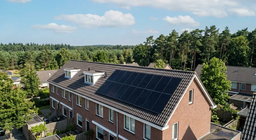 Zwarte zonnepanelen op een rijwoning met de Veluwe op de achtergrond